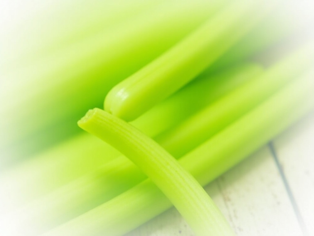 Fresh celery stalks with leaves on white wooden surface